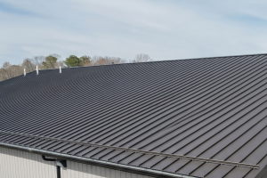 Commercial Roofing Cincinnati - Integrity 1st Roofing Metal standing-seam roof on a building, with a gutter along the edge and a clear sky behind it.