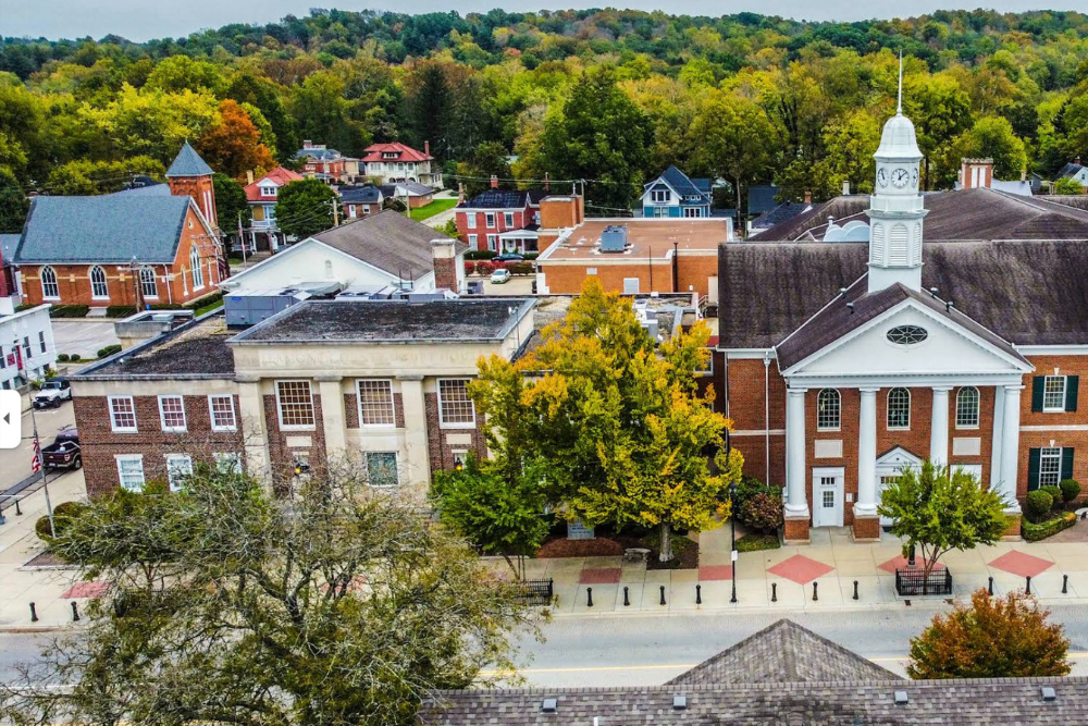 Batavia Ohio - Integrity 1st Roofing Aerial view of a small town with brick buildings and a white church with a clock tower beside colorful autumn trees.