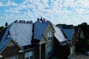 Fan8 - Integrity 1st Roofing Home under construction with workers on a pitched roof laying blue roofing underlayment.
