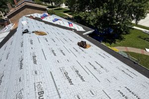 item_2e7a4265-7b70-4568-8488-eb9e64c4d51d - Integrity 1st Roofing Aerial view of a house roof under construction with underlayment sheets and scattered tools, surrounded by grass and trees in the yard