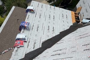 item_36534b49-46f7-4f22-8285-03597af2dee6 - Integrity 1st Roofing Roof being reroofed with white FeBuster underlayment and bundled shingles along the edge of a sloped roof