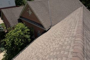 item_f1540716-14ef-4995-92f1-5e5201c7f98d - Integrity 1st Roofing Aerial view of a brick building with a brown shingle roof and surrounding trees.
