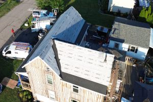 52ec209b-9645-4b69-b21f-7823712c228f-item_4178bfea-efdf-4faa-bd14-6f223956800c - Integrity 1st Roofing Aerial view of a house under roof renovation with new shingles, scaffolding, and construction trucks nearby.