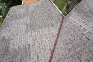 Roof Replacement02 - Integrity 1st Roofing View from above of two intersecting gray asphalt shingle roofs with a metal gutter running along the joint.