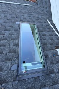 Roof Replacement10 - Integrity 1st Roofing Rectangular skylight in a gray asphalt-shingle roof with a metal frame.